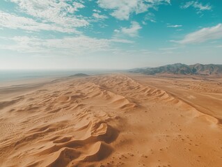 A stunning aerial view of vast golden sand dunes under a bright sky, showcasing the beauty and expanse of a serene desert landscape.