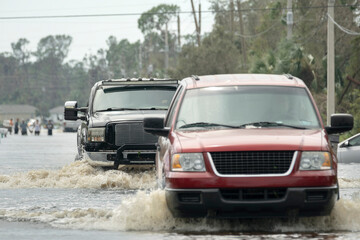 Hurricane flooded street with moving cars and surrounded with water houses in Florida residential...