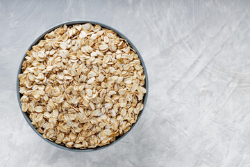 Raw Oat Flakes in Ceramic Bowl on Grey Concrete Background, Healthy Breakfast Ingredient, Top View, Copy Space