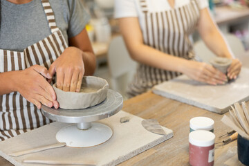 Female hands sculpting product from raw clay in ceramic workshop close-up