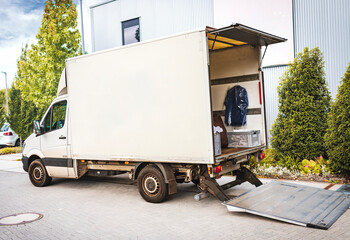 A delivery truck with an open rear door and hydraulic ramp, loaded with various items for...