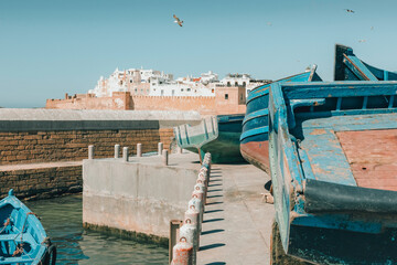 Historical port of Essaouira, Morocco with blue fishing boats docked beside famous ancient fortress...