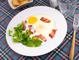 Delicious hearty breakfast with scrambled eggs, bacon and arugula