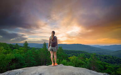 Young woman hiker standing alone on mountain footpath enjoying view of evening nature on wilderness...