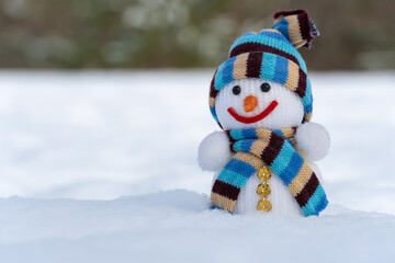 Snowman in christmas clothes stands on white snow in winter forest. Knitted bauble. Christmas and new year holidays decoration. Template for design christmas bauble. Symbol xmas of winter season.