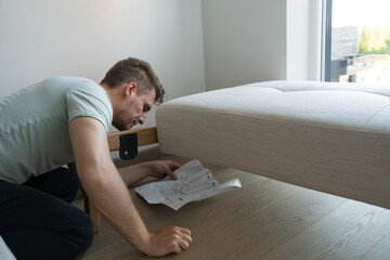 a man reads instructions on how to assemble a sofa at home by himself