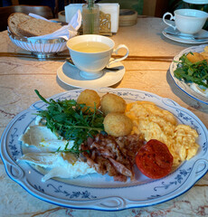 Serving breakfast in a restaurant. A nutritious and healthy breakfast of eggs, greens, vegetables and bacon on a beautiful plate.