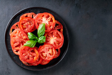 Juicy Tomato Slices with Fresh Basil Leaves on Black Plate, Dark Grey Textured Background, Top View, Copy Space