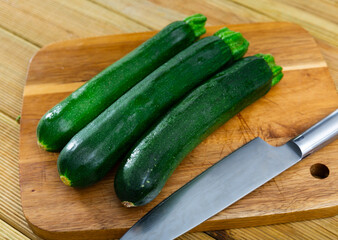 Fresh zucchini whole and sliced on a wooden chopping board. High quality photo