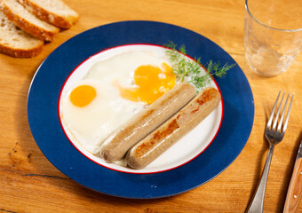 Delicious fried eggs with sausage served on platter for breakfast