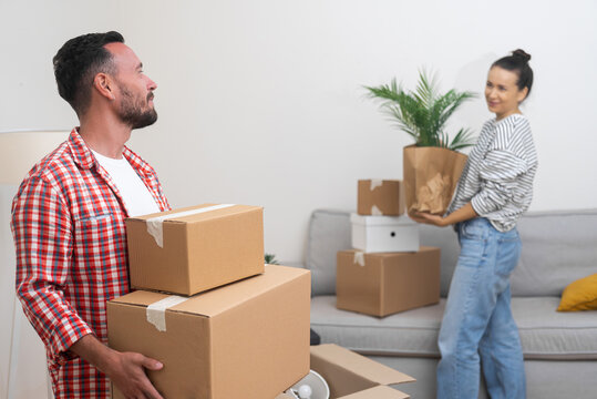 young family satisfaction, carries cardboard boxes from their relocation service into their new living room, cherishing the moments of their move abroad