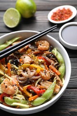 Stir-fry noodles with sea food served on wooden table, closeup