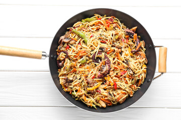 Stir-fry noodles with sea food and vegetables in wok on white wooden table, top view