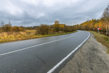 A road with a white line down the middle and a red sign on the side