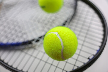 A yellow tennis ball lies against the background of two tennis rackets lying on top of each other on a white background in close-up. Concept of sports and competitions. High quality photo