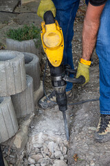 Details of construction site with worker using pneumatic jackhammer for demolishing