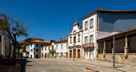 View of typical cobbled street of Portuguese city of Mirandela with old houses and medieval small Church of Mercy on sunny spring day, Braganca
