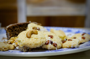 Close-up of homemade glazed cookies with cashews and raisins on a white plate with a blurred background