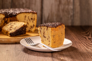 Slice of Brazilian Chocolate Chip Cake with Chocolate Frosting on Plate with Fork
