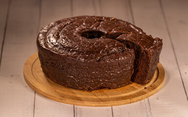 Whole Brazilian Chocolate Covered Cake with Slice Removed on Wooden Board