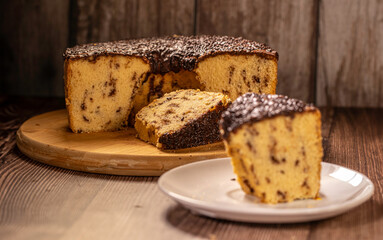 Brazilian Chocolate Chip Cake with Chocolate Frosting on Wooden Board with Slice on Plate