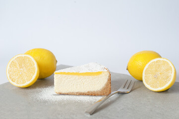 Sliced lemon cheesecake with fresh lemons beside it, showcasing a creamy texture and vibrant yellow color. Perfect dessert presentation.