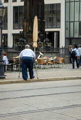 An adult elderly fat man, a sick disabled person with crutches, walks along the street in a...