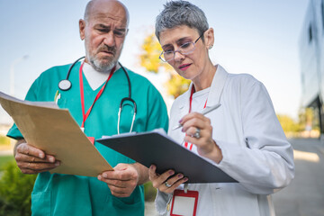 Fototapeta premium senior man and mature woman doctor check information on clipboard