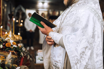 Christian priest with bible in hands, in cassock conducts church service, prays in church. Photo, concept of religion.