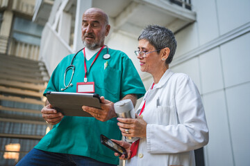 Two doctor use digital tablet on staircase outdoor