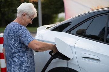Senior Woman Connecting Electric Car to Charging Station