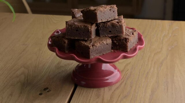 Decadent Chocolate Brownies. stack of rich, fudgy chocolate brownies elegantly displayed on a red dessert stand. This indulgent dessert is perfect for bakery promotions, dessert social media content