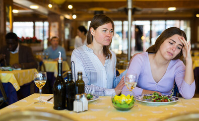 Woman calming her female friend down in restaurant because she's feeling depressed.