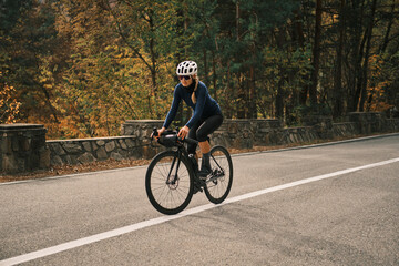 Woman cyclist rides her bike on a scenic autumn road.  Perfect for active lifestyle, sports, and travel themes.