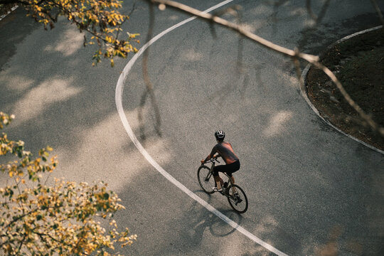 Cyclist on a scenic road curve. Aerial view of a person cycling through a vibrant landscape. Perfect for travel, sport, or lifestyle projects. Romania. Carpathian Mountains. Transylvania