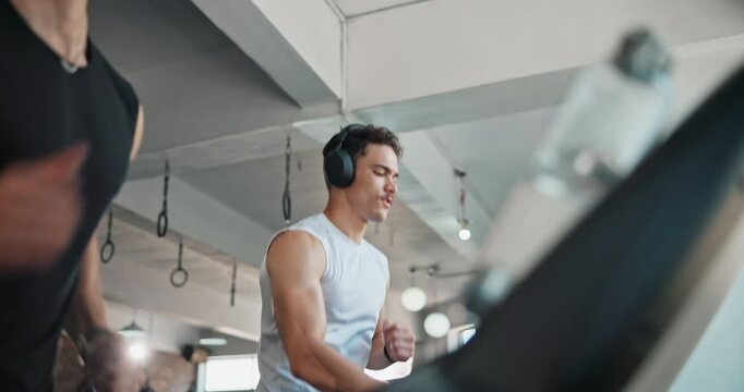Man, headphones and running on treadmill at gym with low angle, speed or music at fitness club. Person, machine or equipment with streaming, subscription and listen with workout, training or exercise