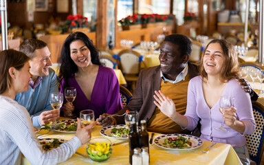 Smiling couple on friendly meeting over dinner with wine in restaurant