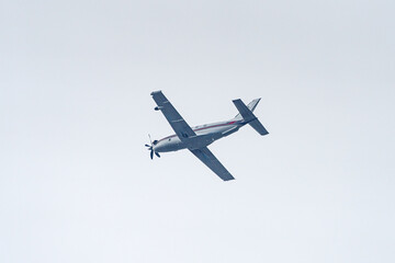 A plane with a propeller flies high in the sky.