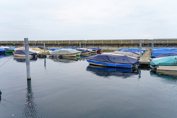 Boats and yachts covered with awnings and moored for wintering at the pier in a private port.