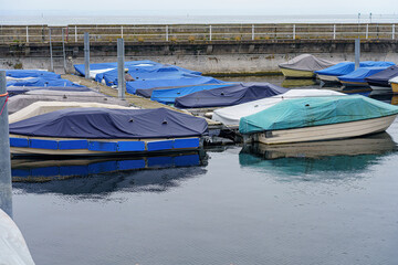 Boats and yachts are covered and prepared for winter on the dock in a private port.