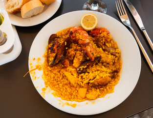 Appetizing traditional paella with meat, chicken and seafood on platter