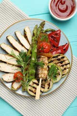 Delicious grilled vegetables and cut chicken meat served with sauce on light blue wooden table, flat lay