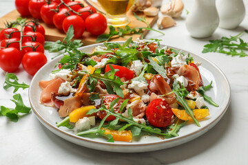 Tasty salad with arugula, cheese and vegetables on white table, closeup
