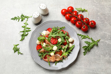 Tasty salad with arugula on grey textured table, flat lay