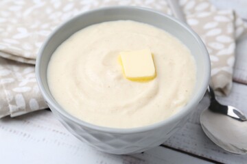 Tasty cooked semolina porridge with butter on white wooden table, closeup
