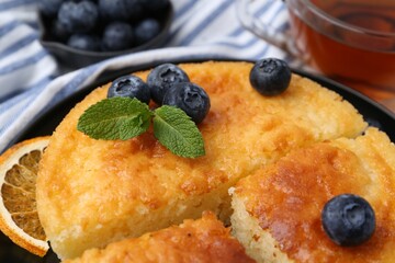 Delicious semolina cake with blueberries and orange slices on table