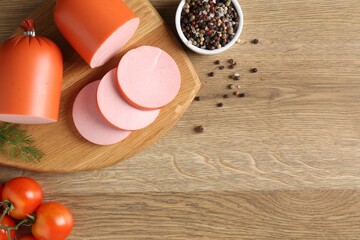 Tasty boiled sausages, spices and tomatoes on wooden table, top view. Space for text
