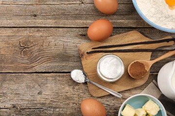 Baking powder in bowl and other products on wooden table, flat lay. Space for text