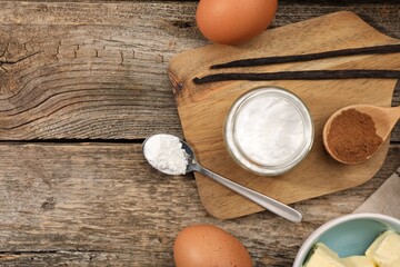 Baking powder in bowl and other products on wooden table, flat lay. Space for text