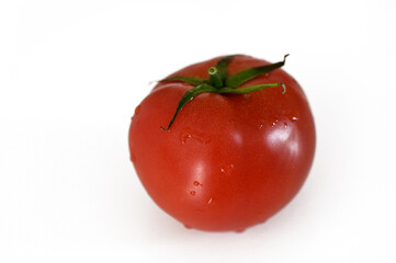 Fresh, ripe red tomato with dew glistening on its surface against a clean white background